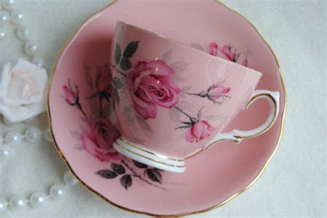 A Pink Tea Cup And Saucer With Roses On It