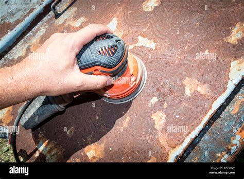 Mans Hand Operates A Discorbital Sander To Remove Paint And Rust