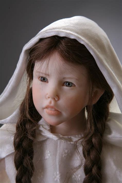 A Close Up Of A Doll With Long Hair Wearing A White Dress And Bonnet On