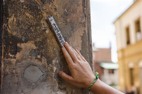 Hand Touching Mezuzah At The Entrance To The House Stock Photo