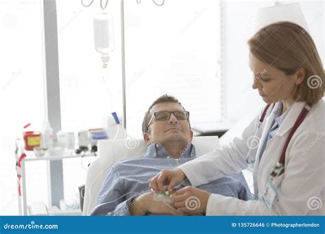 Doctor Adjusting Saline Iv Drip For Mature Patient In Hospital Stock