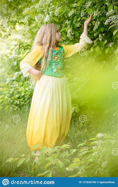 Blond Young Girl Posing In A Yellow Green Dress Near Birch Trees Stock