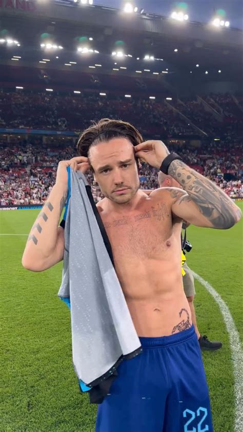 A Man With No Shirt On Standing In Front Of A Soccer Field Holding A Towel
