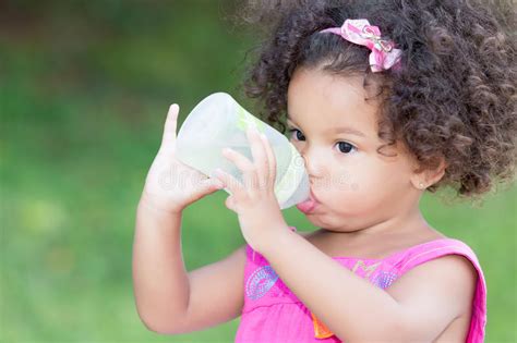 Cute Latin Girl Drinking From A Baby Bottle Stock Image