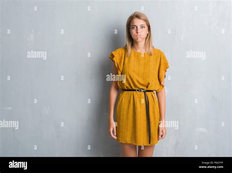 Beautiful Young Woman Standing Over Grunge Grey Wall Wearing A Dress