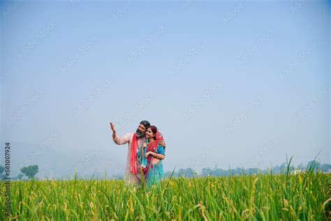 Indian Farmer With Wife Spreading Hand And Giving Expression At Field