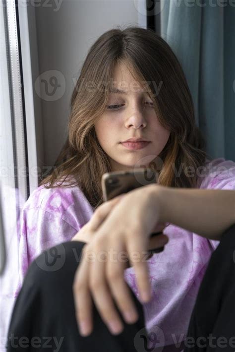A Cute Smiling Caucasian Teenage Girl Using A Smartphone Dependence On