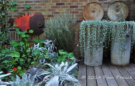 An Outdoor Garden Area With Various Plants And Metal Containers On The