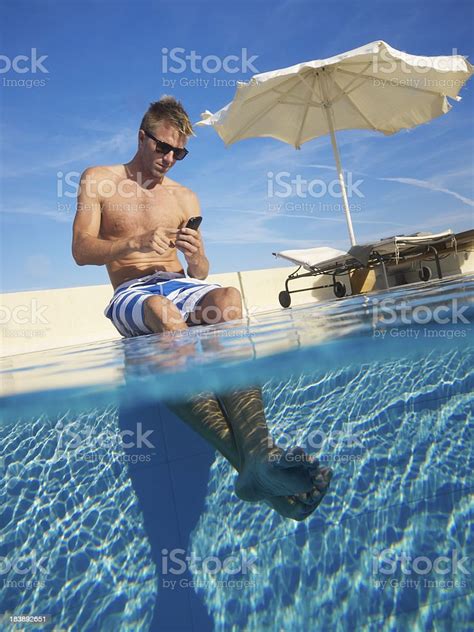 Young Man Relaxing Texting On Smartphone Feet In Swimming Pool Stock