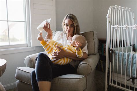 Mother Trying To Bottle Feed Her Distracted Baby By Stocksy
