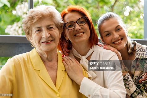 Joyful Mature Woman Cuddling Her Mother And Daughter And Smiling At