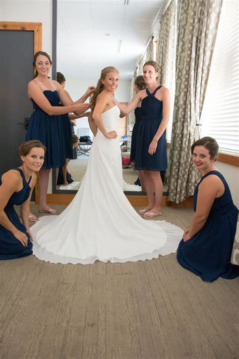 bridesmaids helping the bride put on her wedding dress