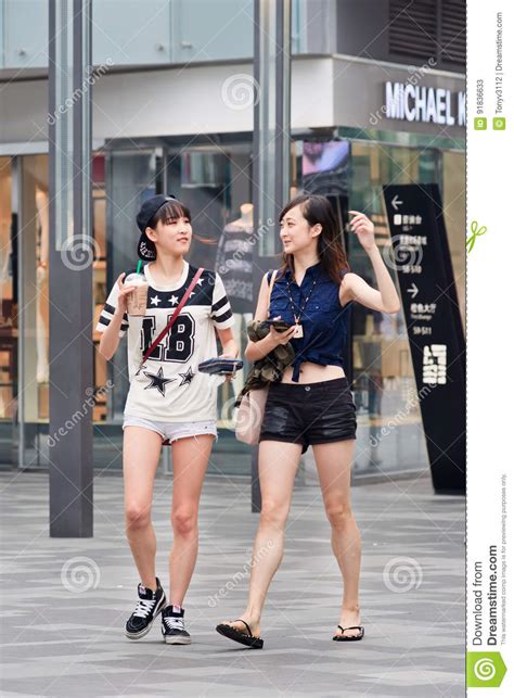 Fashionable Girls Walk In The Village Shopping Area