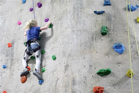 Young Girl Climbing Rock Wall At Indoor Rock Climbing Gym Stock Photo
