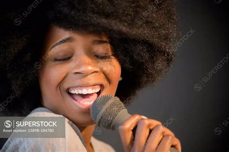Mixed Race Woman Singing Into Microphone Superstock
