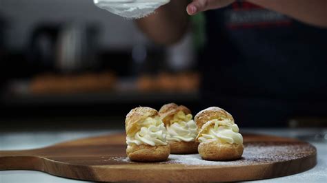 Bakery Pastry Chef Sprinkling Powdered Sugar Choux Cream Puff On Wood