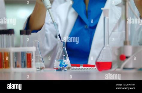 Female Scientist Pouring Reagent In Lab Flask Scientist Doing Chemical