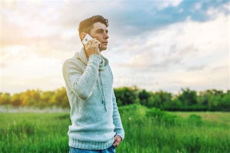 Young Man Businessman Talking At Mobile Phone Outside On A Grass Field