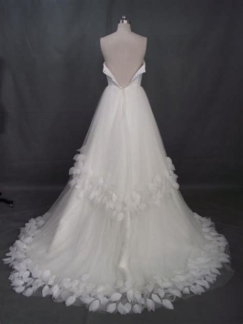 A White Wedding Dress With Flowers On The Skirt And Neckline Is