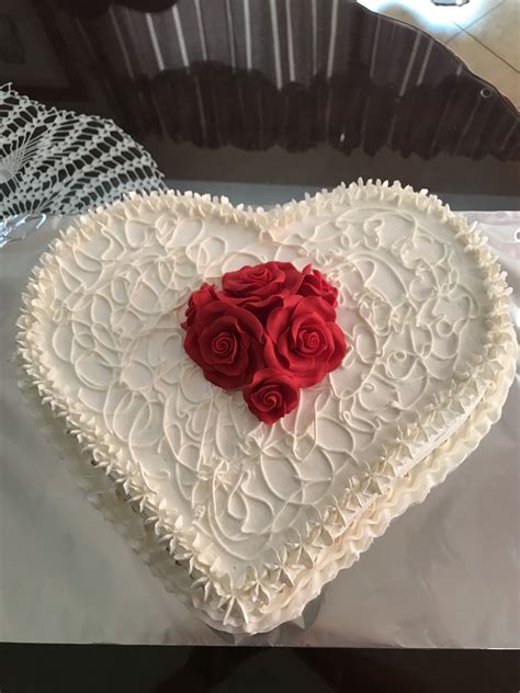 A White Heart Shaped Cake With Red Roses On Top