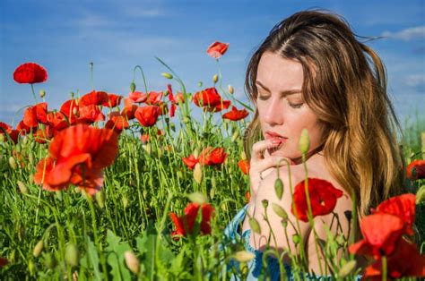 A Young Cheerful Beautiful Girl Walks In A Poppy Meadow Among Red