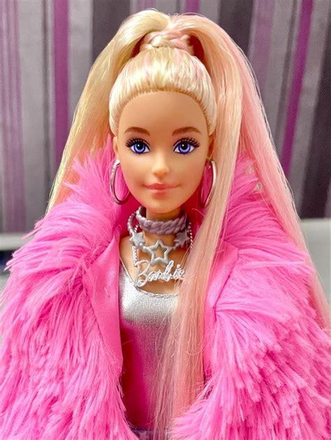 A Barbie Doll With Blonde Hair And Blue Eyes Wearing A Pink Fur Coat Over Her Shoulders