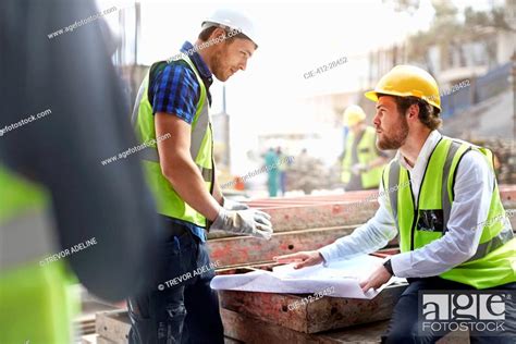 Construction Worker And Engineer Reviewing Blueprints At Construction