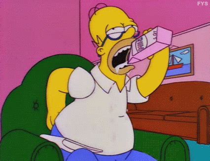 The Simpsons Is Sitting In A Green Chair And Holding A Pink Object Up To His Mouth