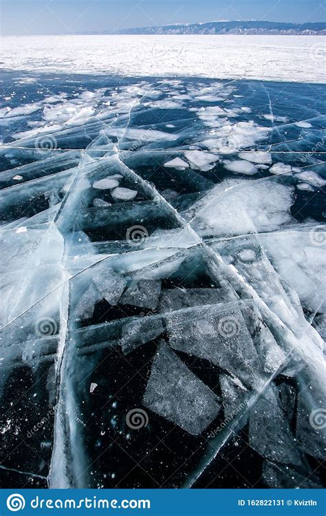 Transparent Dark Ice On Lake Baikal With Frozen Pieces Of Ice And Large