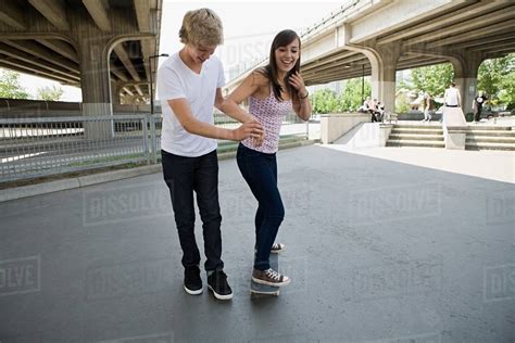 Boy Helping Girlfriend To Skate Stock Photo Dissolve