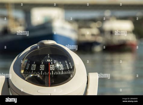 Close Up Of A Compass On A Boat Passing By The Anchored Ships Stock