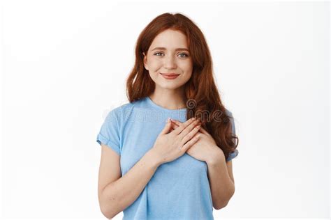 Portrait Of Hopeful Smiling Redhead Woman Holding Hands On Heart And Looking Tender At Camera