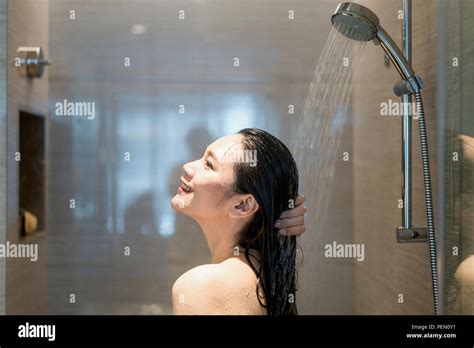 Young Asian Woman Taking A Shower In The Bathroom With Shower Head Looking Happy And Relax