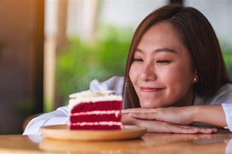 A Beautiful Young Asian Woman Looking At A Piece Of Red Velvet Cake In Wooden Tray On The Table