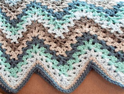 A Crocheted Blanket Is Laying On Top Of A Brown Surface With Blue