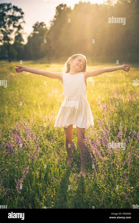 Happy Girl Dancing On Flower Meadow At Evening Twilight Stock Photo Alamy