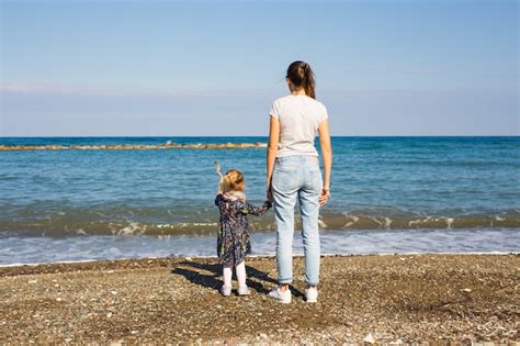 Vista Posterior De La Madre Y Su Pequeña Hija Mirando El Mar En Verano