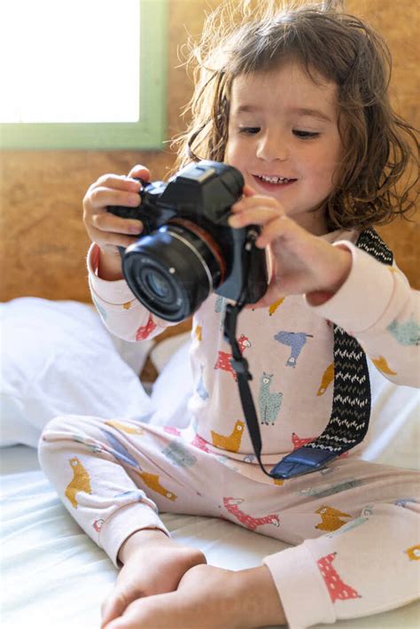 Süßes Kleines Mädchen Im Pyjama Im Bett Mit Einer Kamera Lizenzfreies Stockfoto