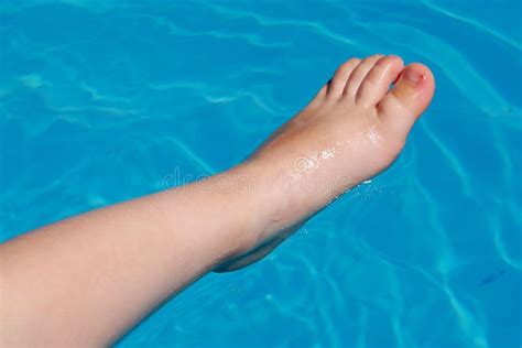 Child Leg With Foot Half Submerged In Blue Swimming Pool Water Stock