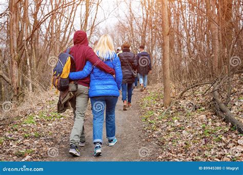 Group Of Friends Walking With Backpacks In Spring Forest From Back Backpackers Hiking In The