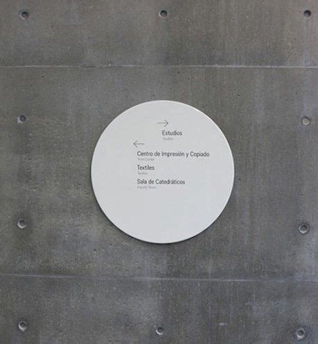 A White Plaque On The Side Of A Building With Words Written In Spanish And English