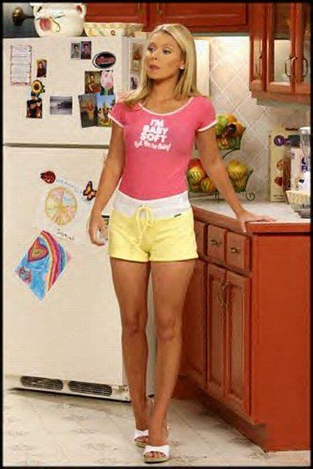A Woman Standing In Front Of A Refrigerator Wearing Yellow Shorts And A