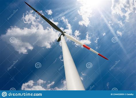 Wind Turbine Against A Blue Sky With Clouds And Sun Rays Renewable