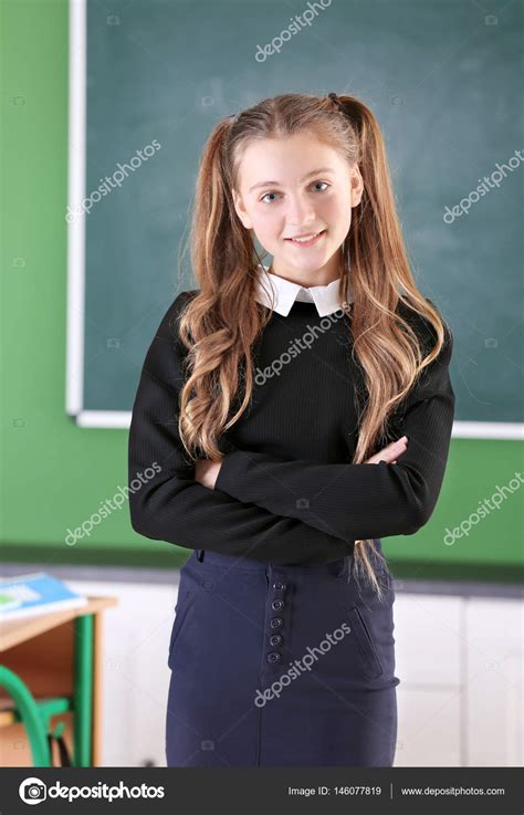Teenage girl in school uniform standing in classroom — Stock Photo © belchonock #146077819