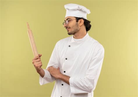 Free Photo Pleased Young Male Cook Wearing Chef Uniform And Glasses Holding And Looking At