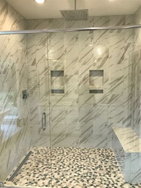 calacatta gold marble tile on the shower wall and a river rock mix on the shower floor