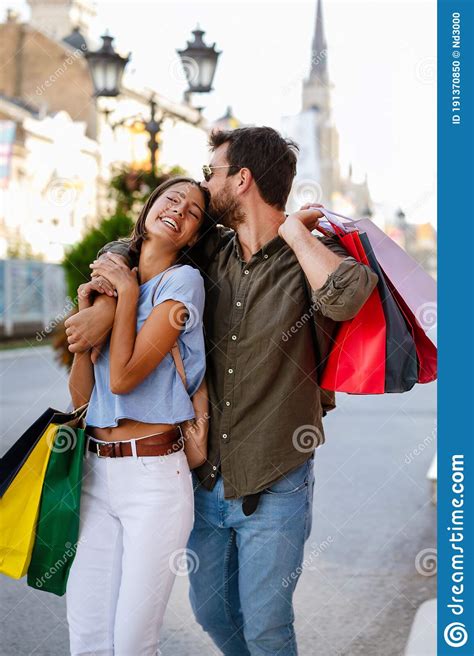 Beautiful Young Loving Couple Walking By The Street While Shopping And