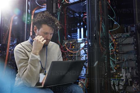 Focused Male It Technician Using Laptop In Server Room Stock Photo