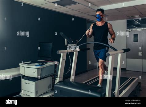 Male Runner With Mask Running On Treadmill Machine Testing His Performance Athlete Examining