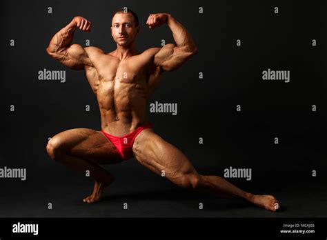 Young Male Bodybuilder Standing Knee Bend One Leg Squat Showing Front Double Biceps Pose